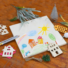 Children's drawing of a house, sun, and trees on a wooden surface with decorative items.