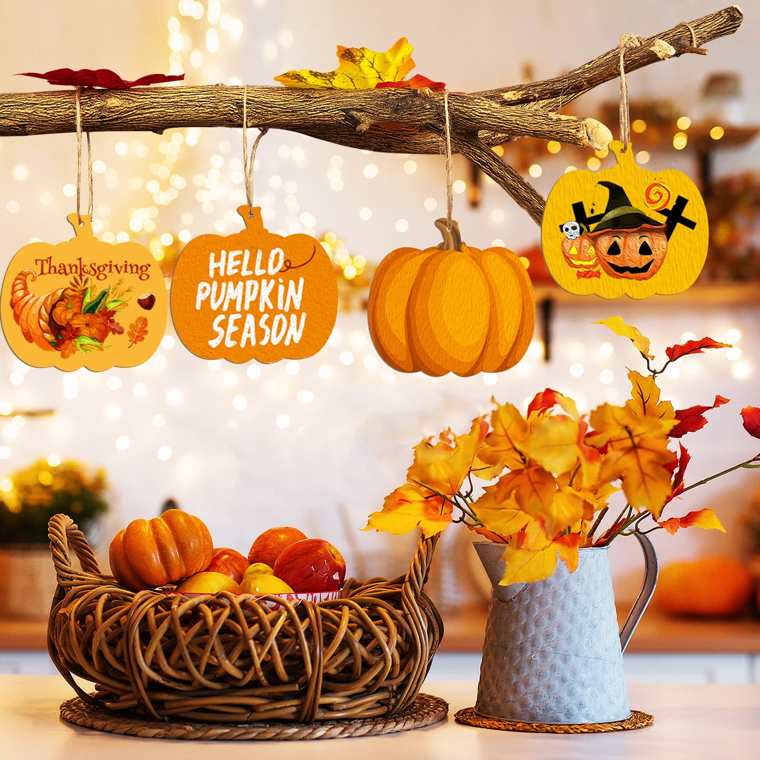 Decorative setup with pumpkins, leaves, and autumn-themed signs on a branch against a blurred festive background.