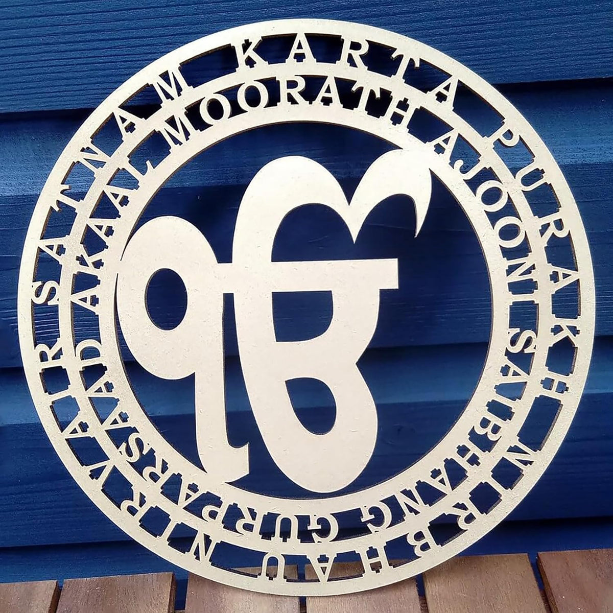 Decorative metal sign with circular design and text on a blue wooden background