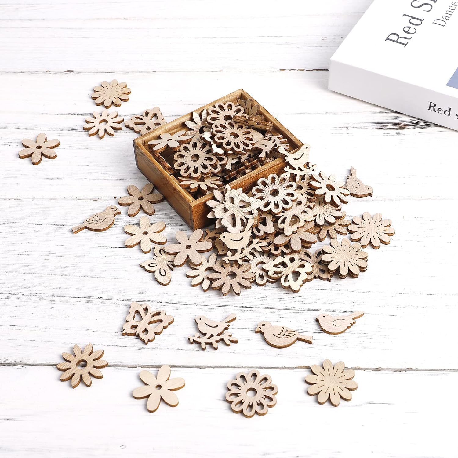 Wooden flower and bird shapes scattered on a white wooden surface with a small box.