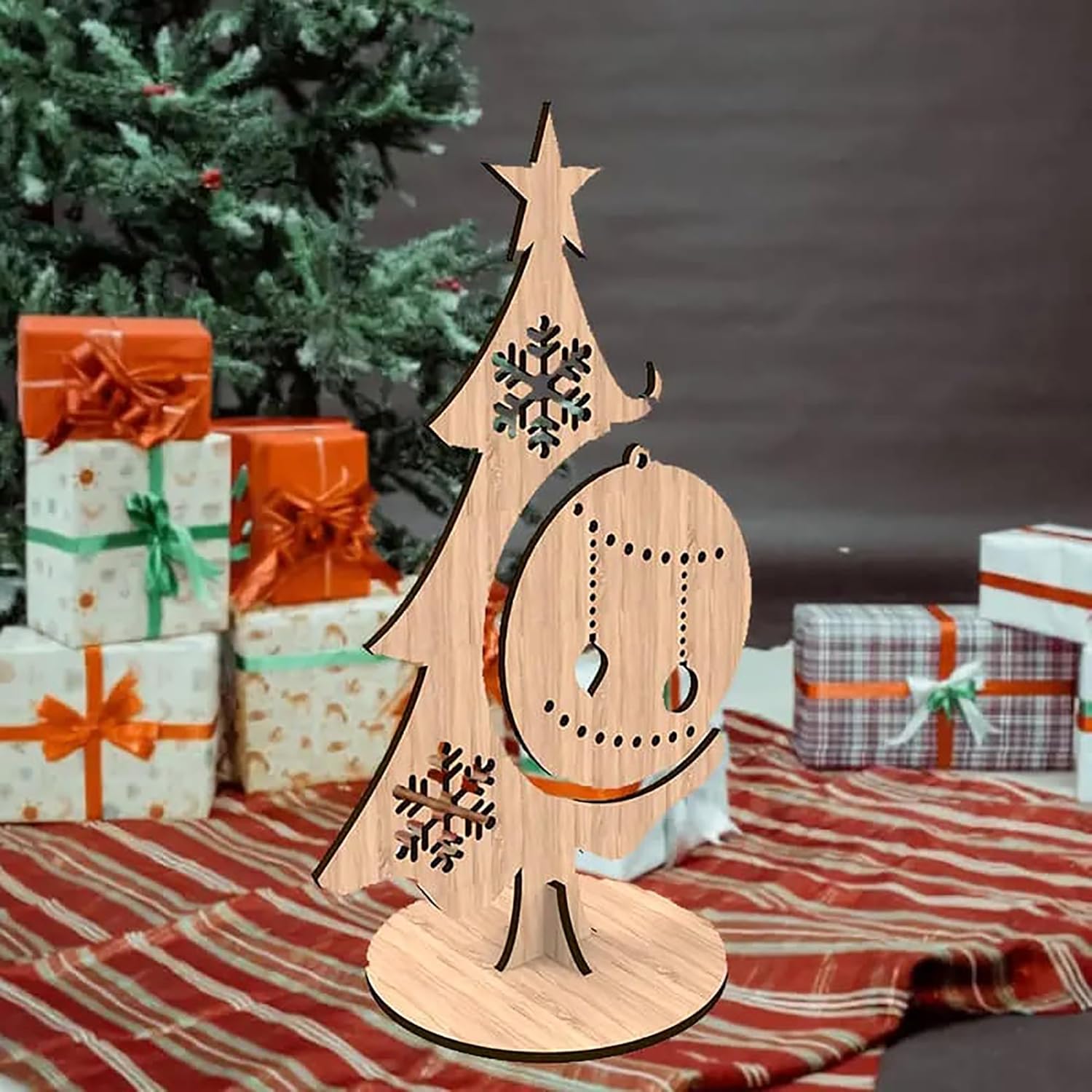 Wooden Christmas tree decoration with snowflakes on a table with presents and a tree in the background.