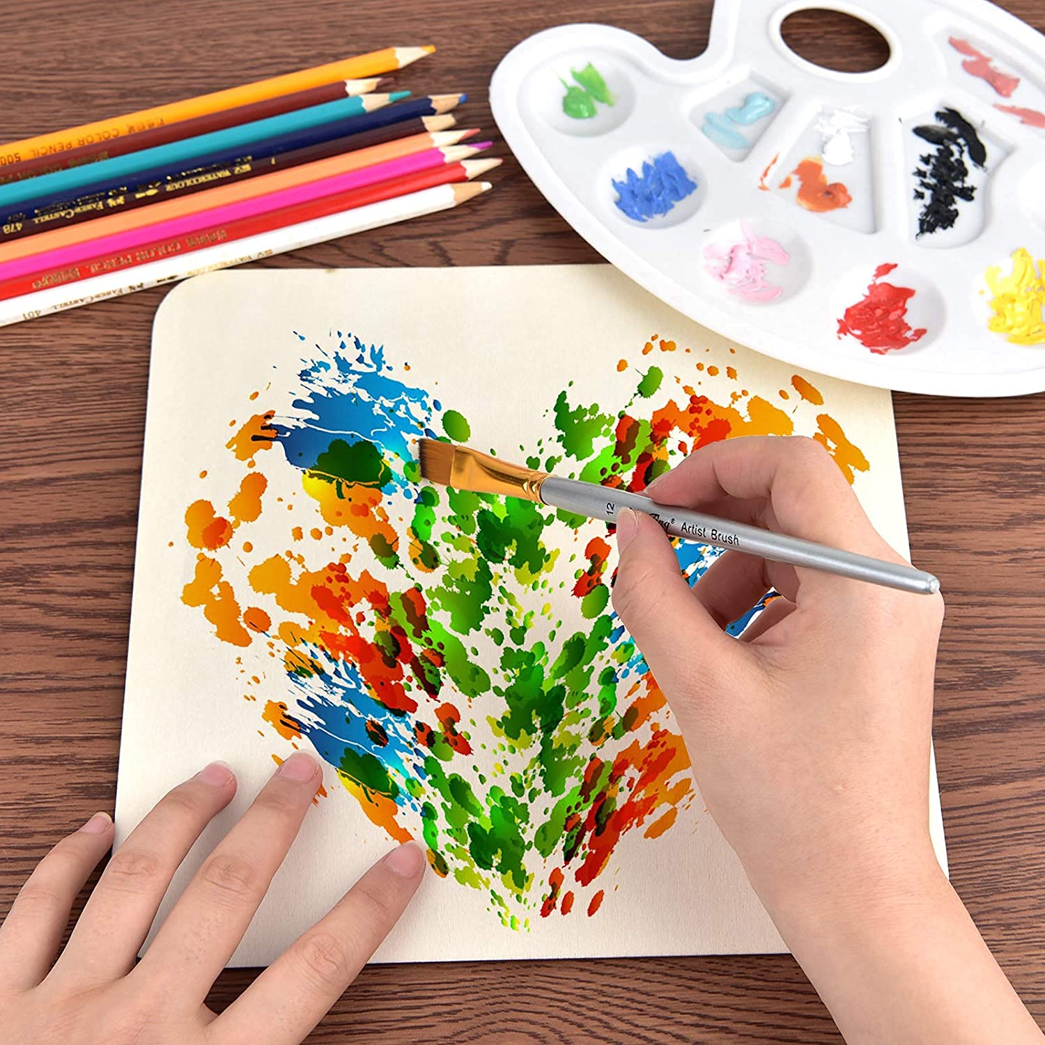 Person painting a colorful abstract design on paper with a paintbrush, surrounded by colored pencils and a palette.