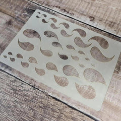 Metallic decorative stencil with wavy patterns on a wooden surface