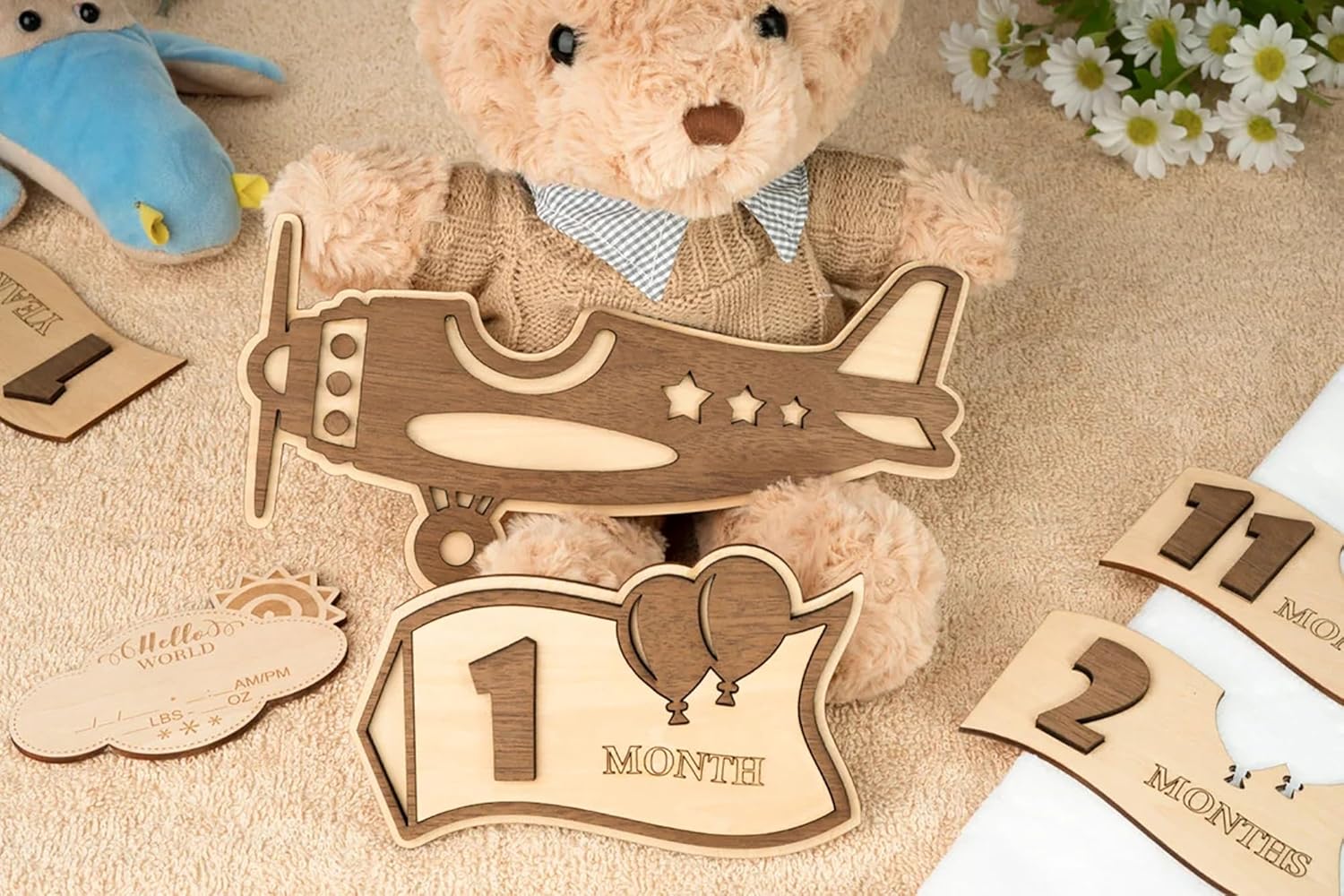 Teddy bear with wooden airplane and milestone cards on a textured surface