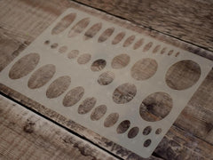 Metal template with circular cutouts on a wooden surface