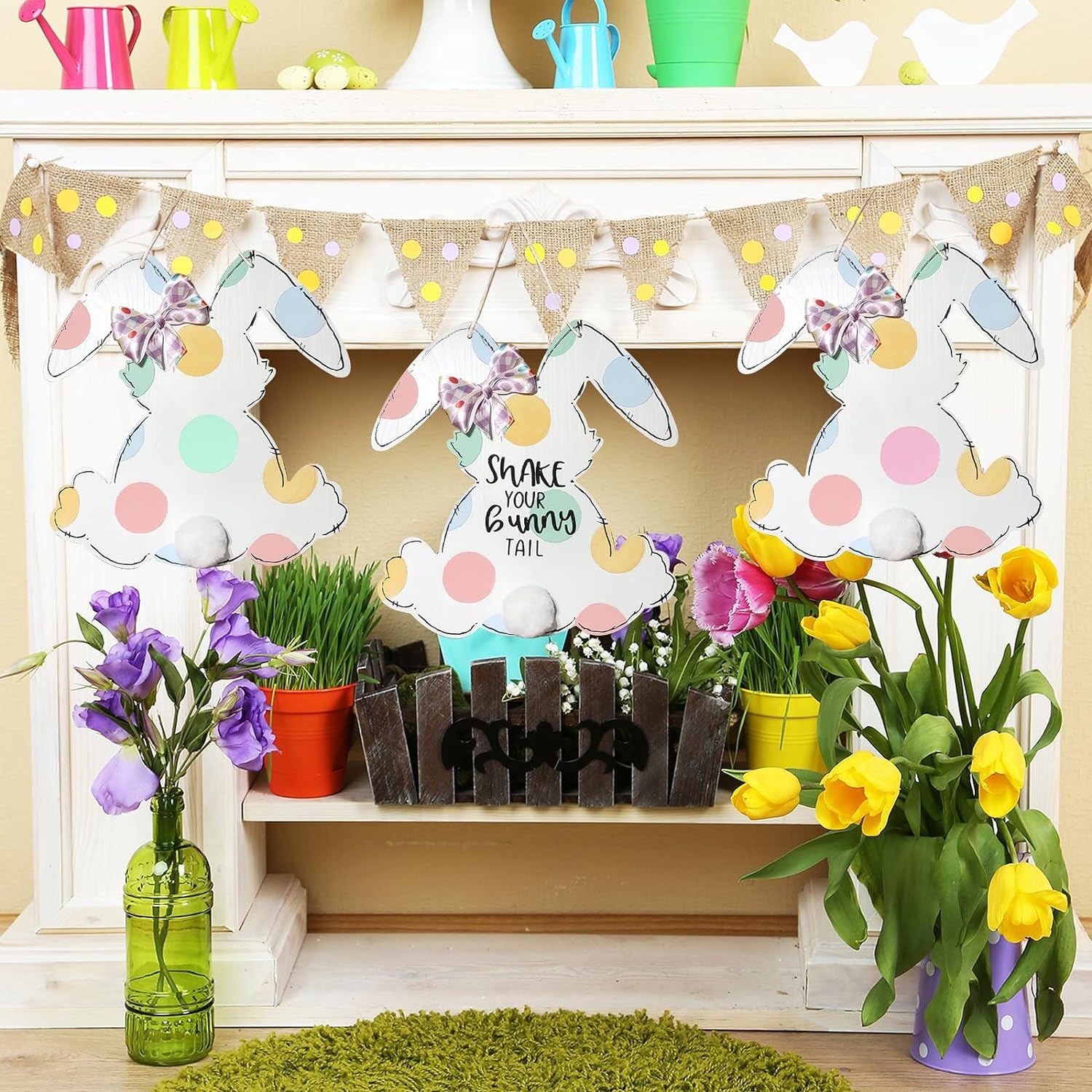 Decorative Easter scene with bunny cutouts, flowers, and a banner on a shelf.