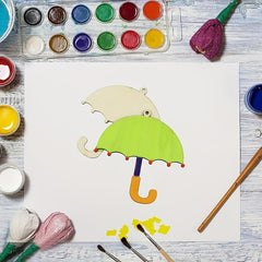 Colorful paper umbrella craft on a white sheet with paint supplies around