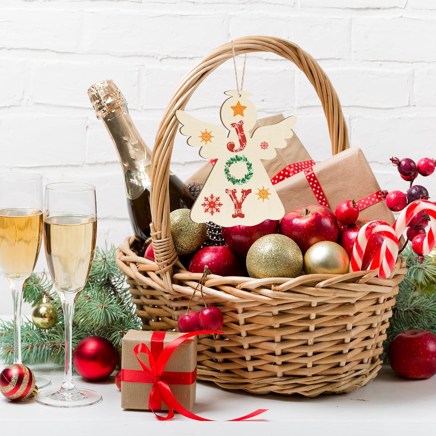 Christmas gift basket with champagne, ornaments, and a 'JOY' sign on a white background