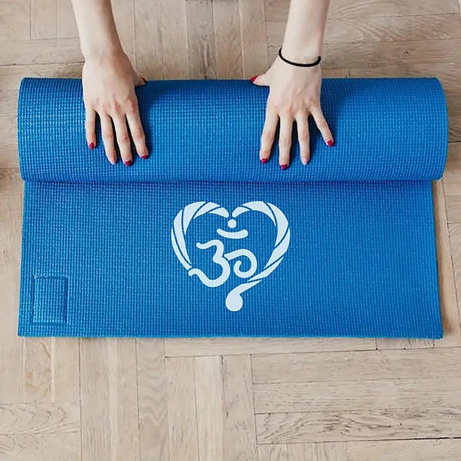Blue yoga mat with Om symbol being rolled out on a wooden floor