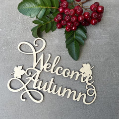 Decorative sign with 'Welcome Autumn' text on a gray background with berries and leaves.