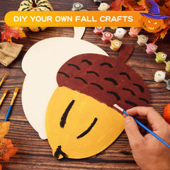 Person painting a craft acorn on a wooden table with fall-themed decorations.