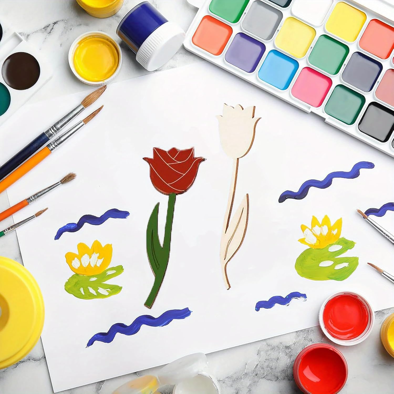 Artistic depiction of flowers and wavy lines on a white sheet with watercolor paints and brushes.