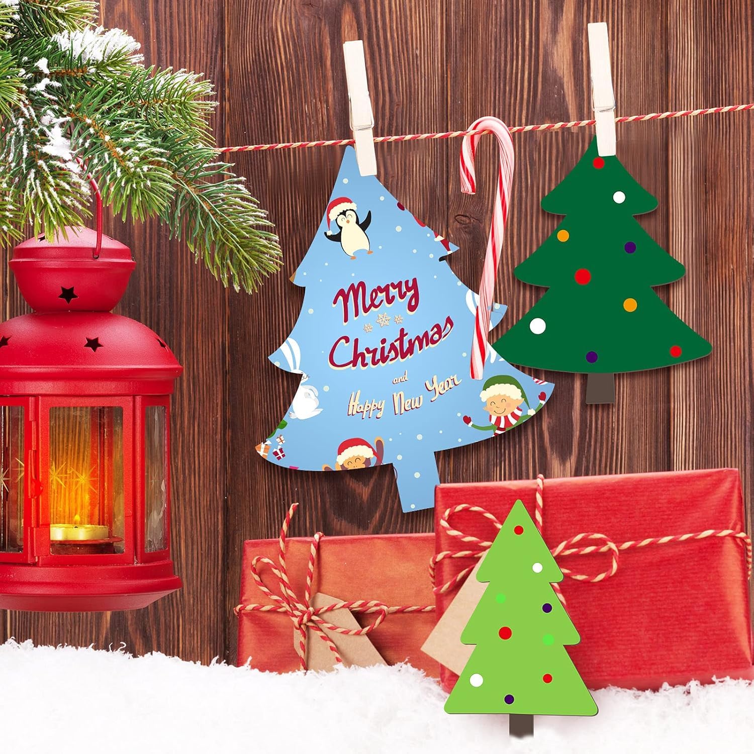 Christmas decorations including a red lantern, gift boxes, and tree-shaped signs with text on a wooden background.