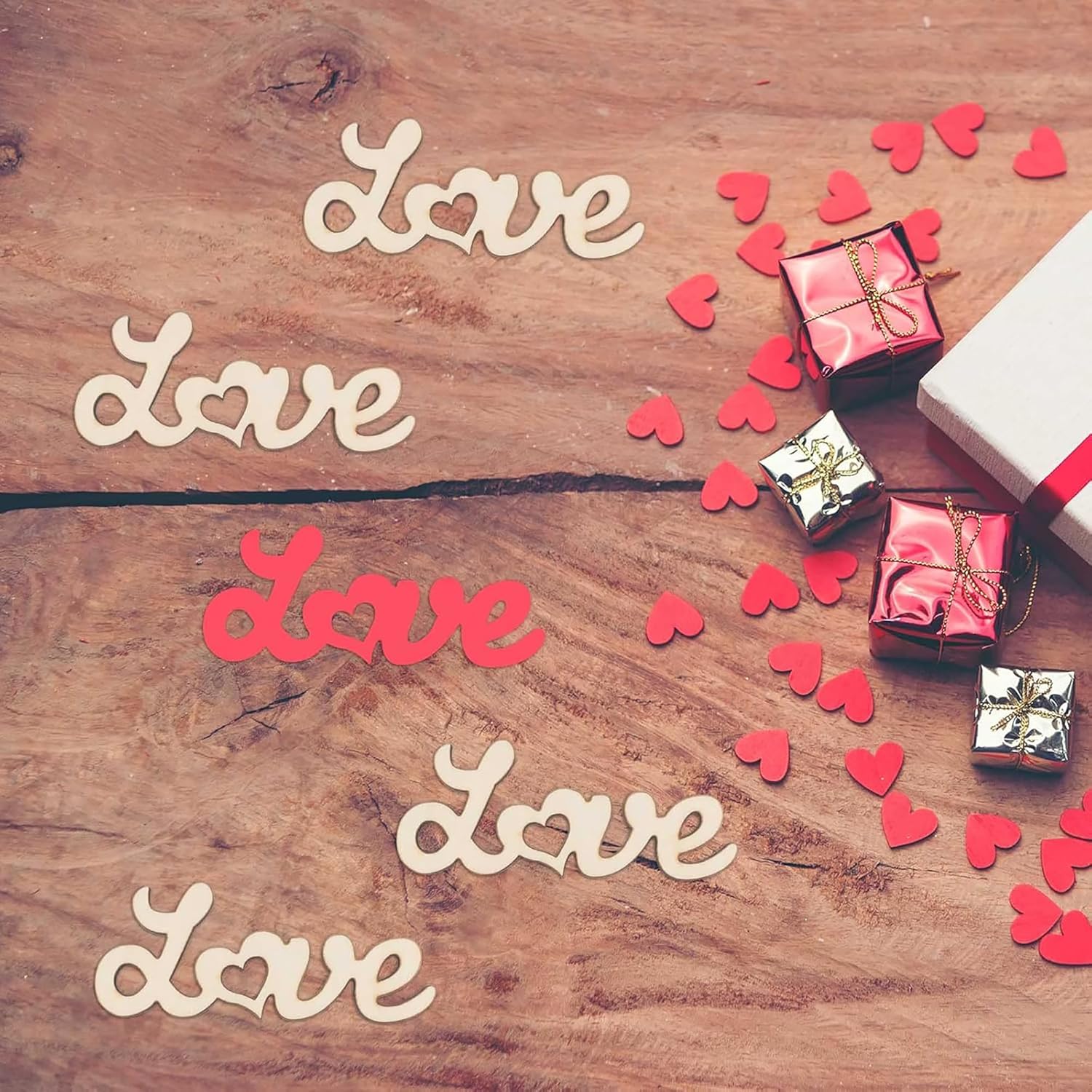 Wooden surface with 'love' text, small gift boxes, and red hearts.