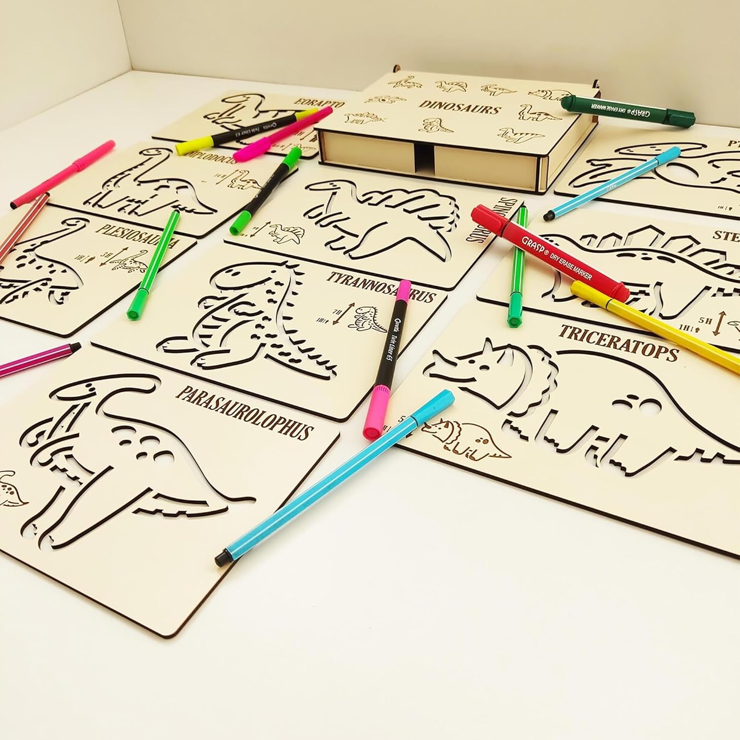 Coloring book with dinosaur illustrations and markers on a white surface