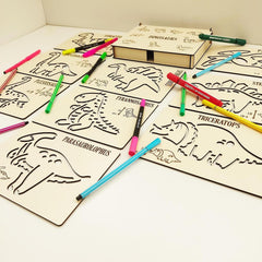 Coloring book with dinosaur illustrations and markers on a white surface