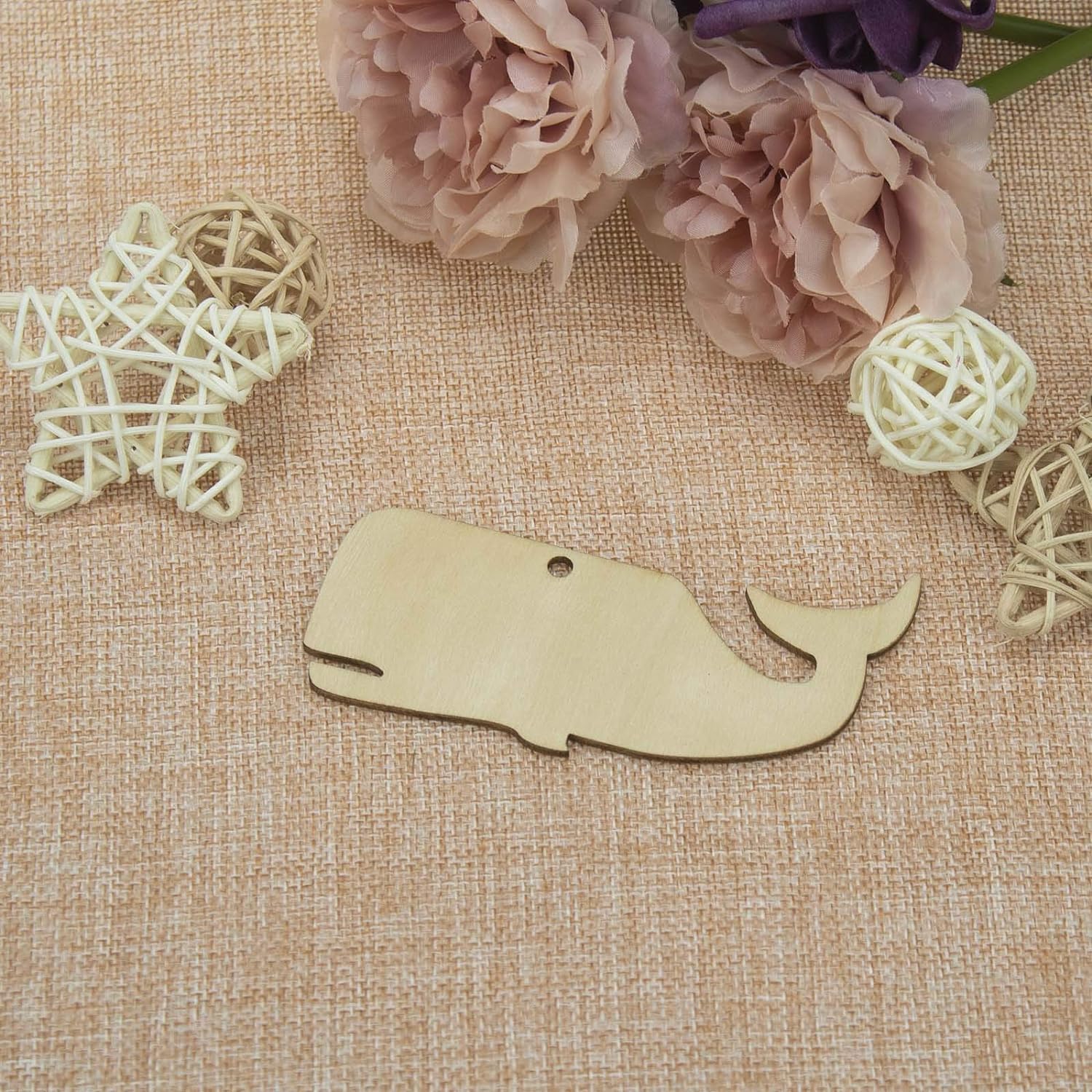 Wooden whale-shaped ornament on a textured fabric background with decorative elements.