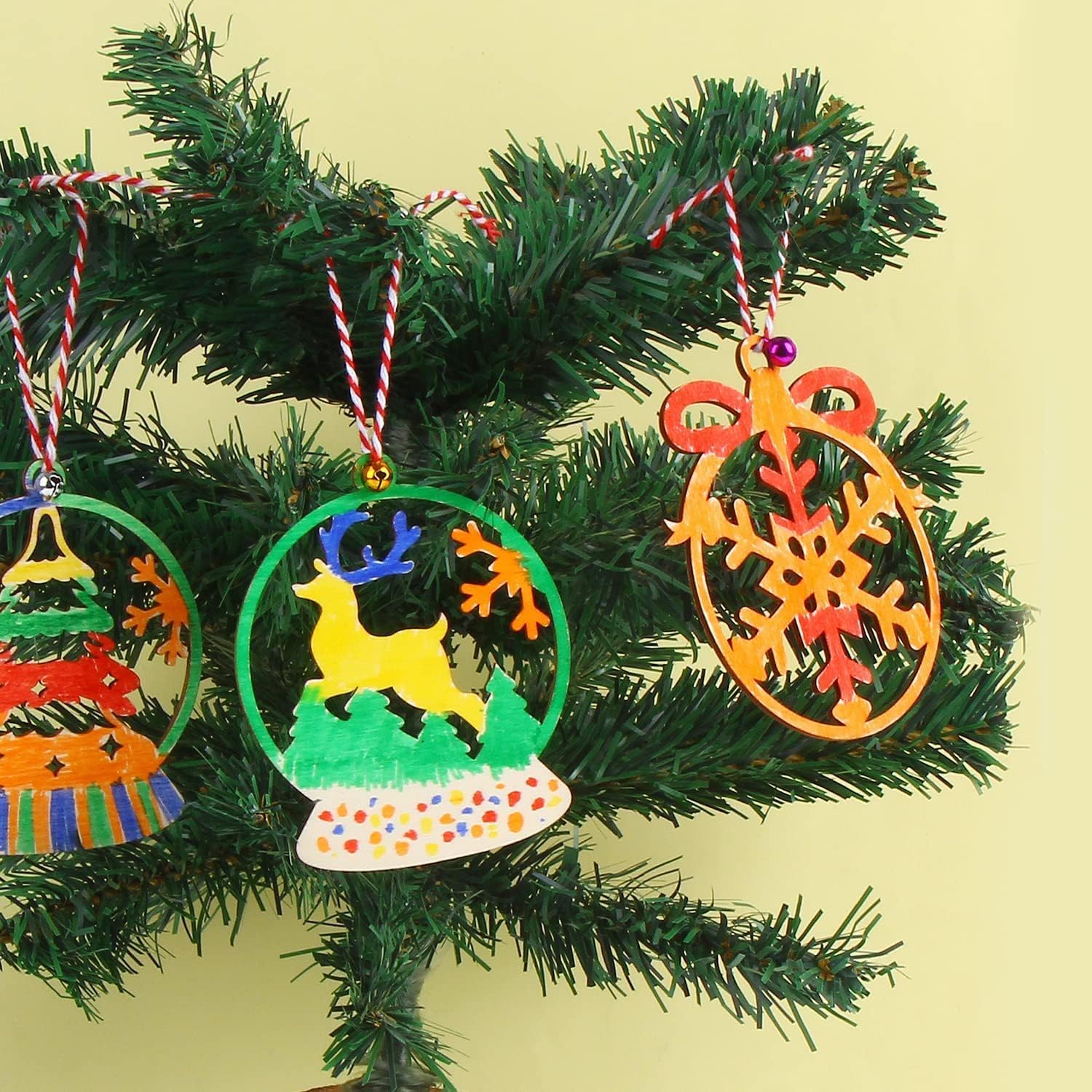 Colorful Christmas tree ornaments on a green branch against a yellow background
