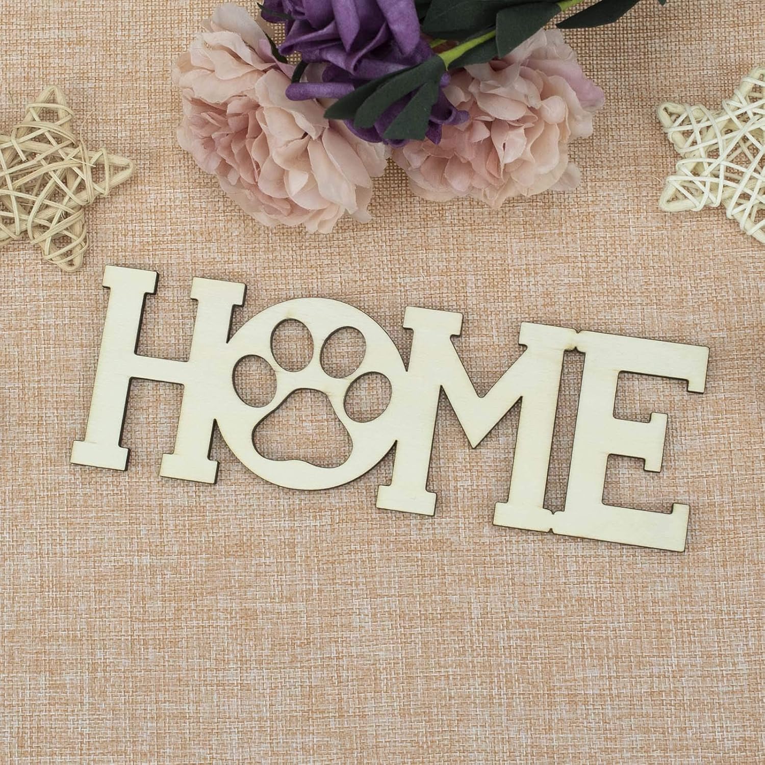 Wooden 'HOME' sign with paw prints on a textured surface with flowers and decorative elements.