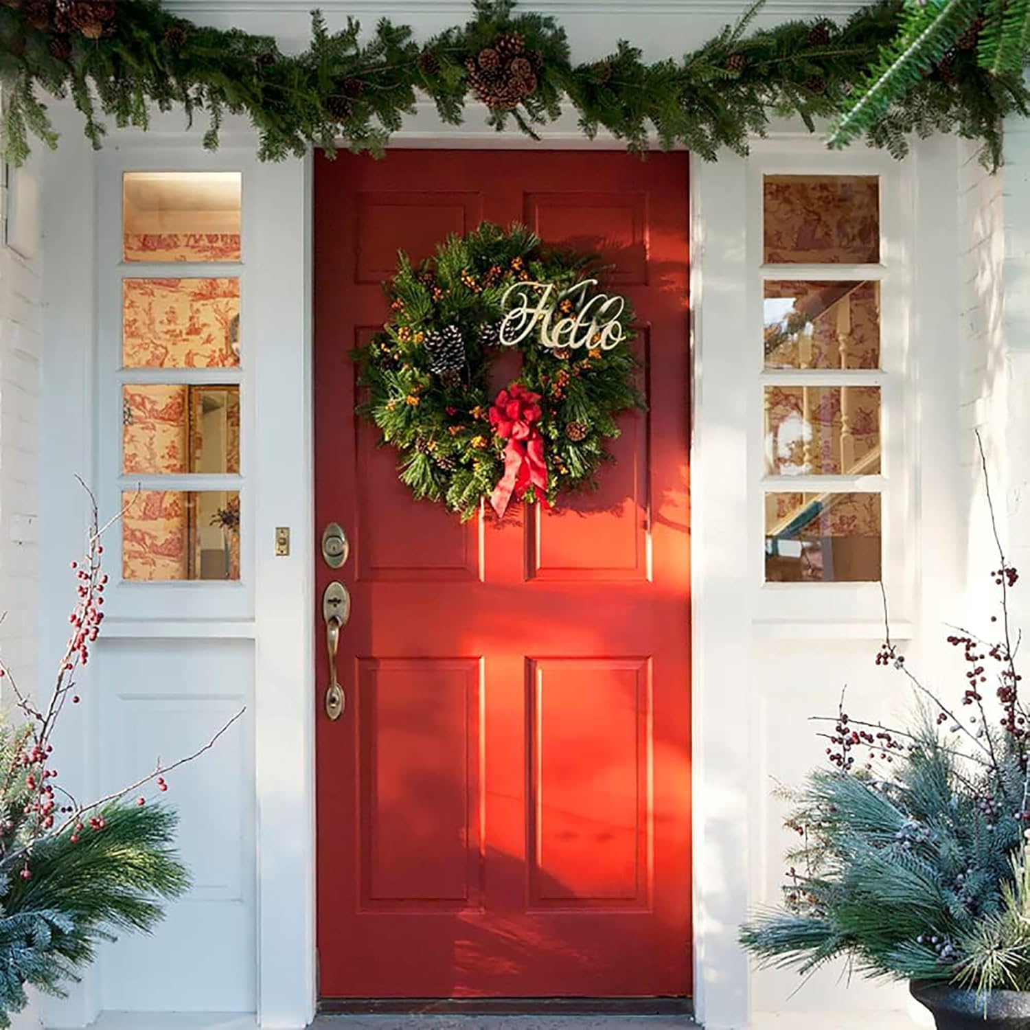 Red door with Christmas wreath and decorations on a white house exterior.