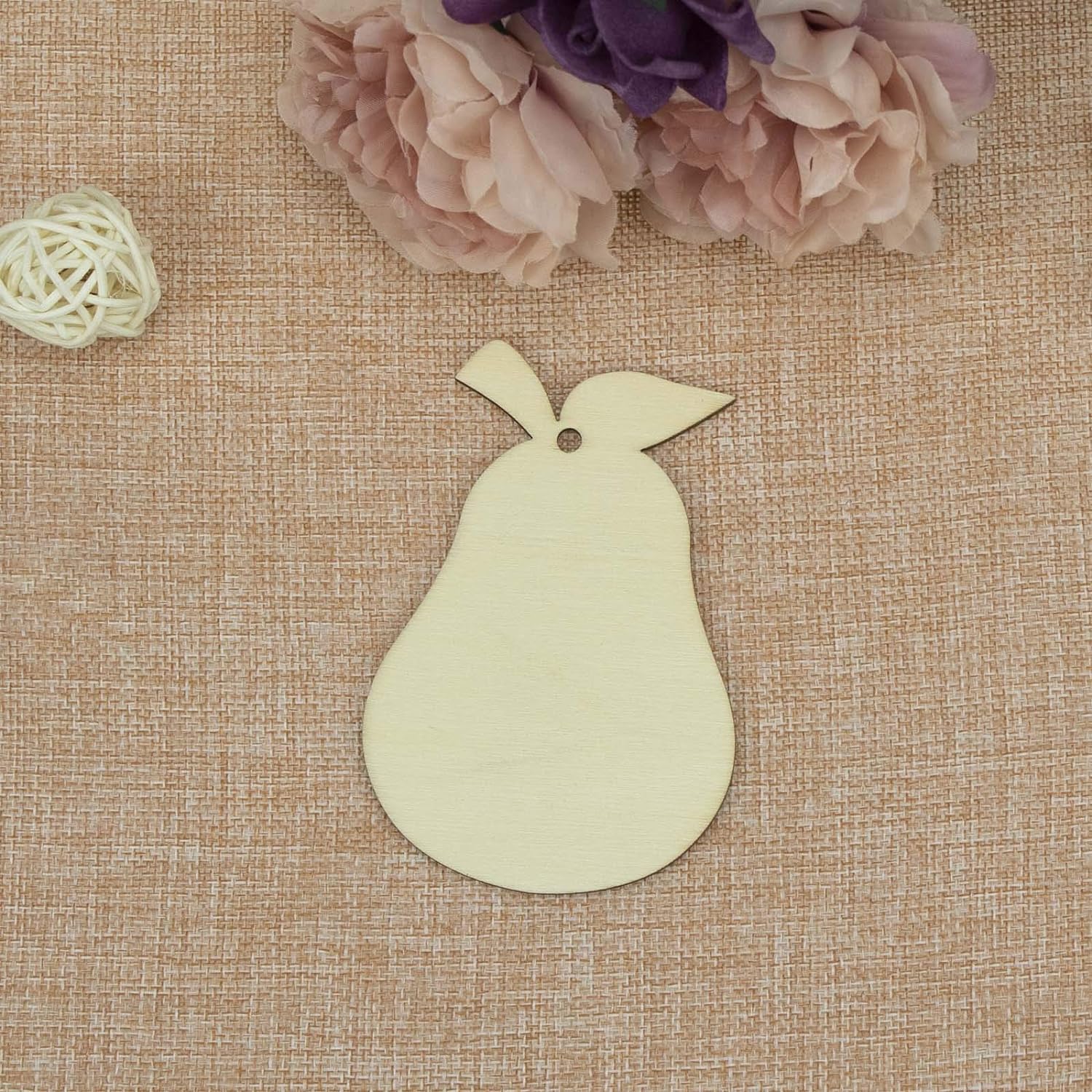 Light green pear-shaped tag on a textured brown surface with flowers in the background