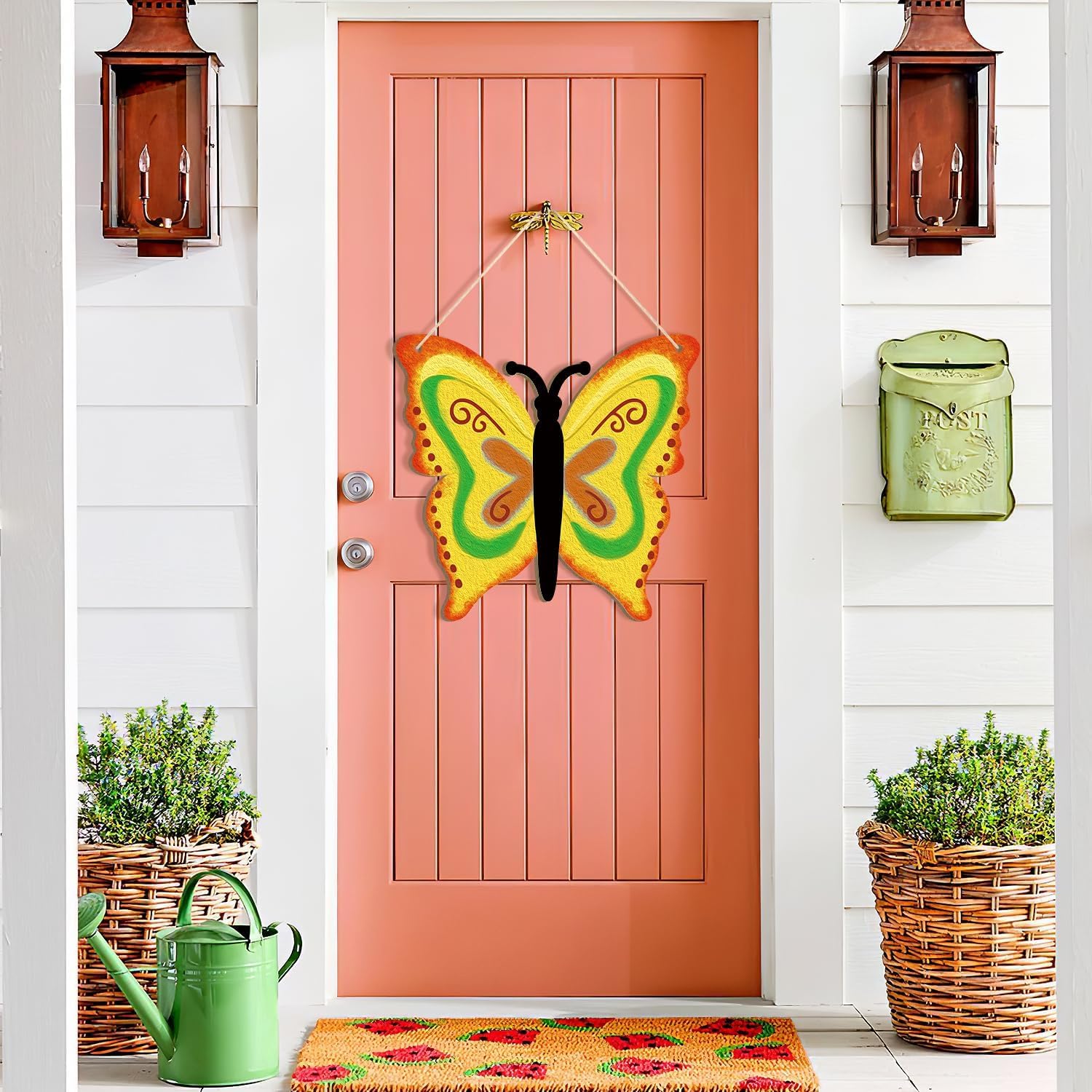 Pink door with a colorful butterfly decoration, green watering can, and planters on a white wall.