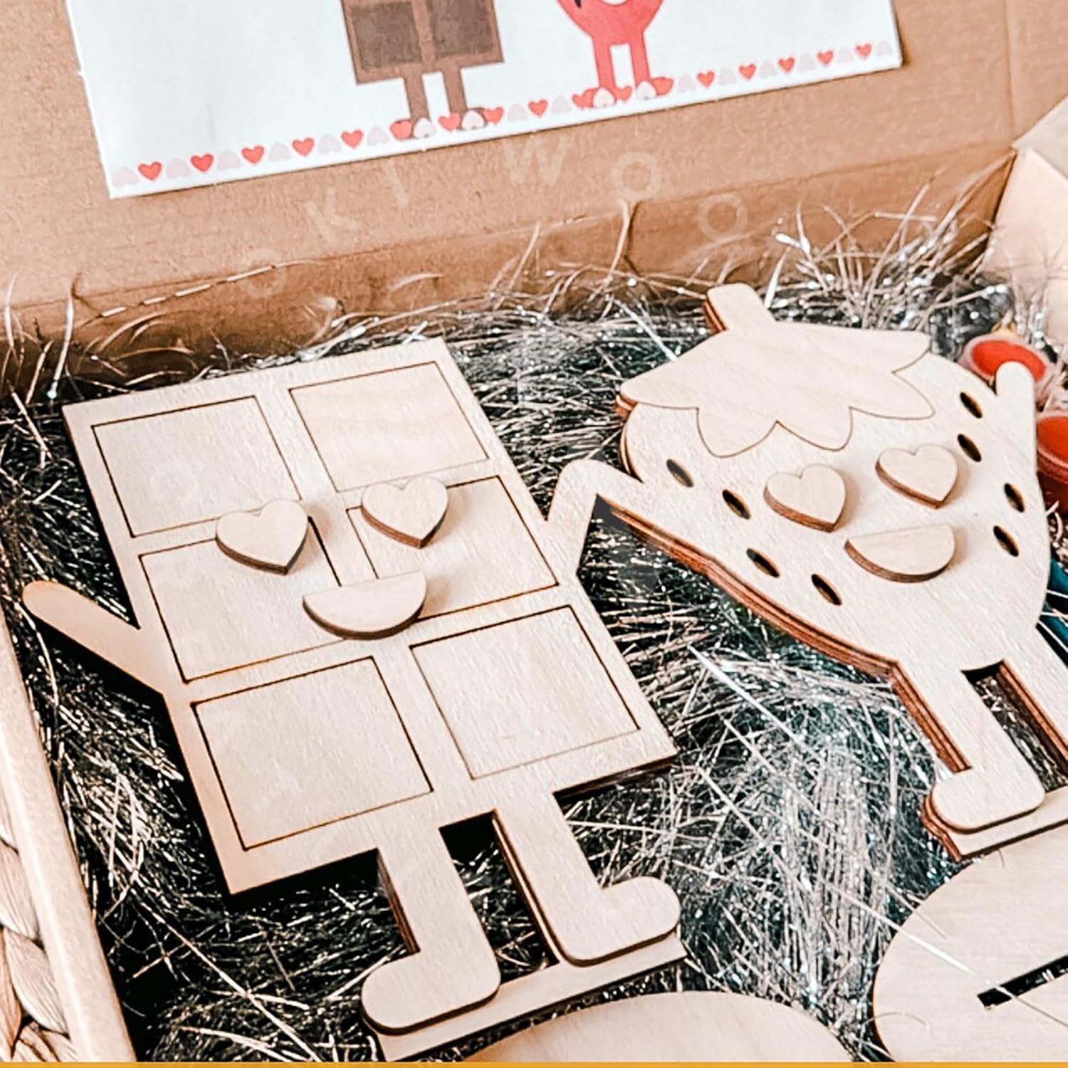 Wooden puzzle pieces shaped like a house and hearts on a box with packaging materials.