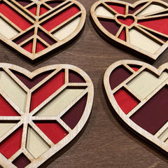 Four geometric heart-shaped wooden decorations on a wooden surface