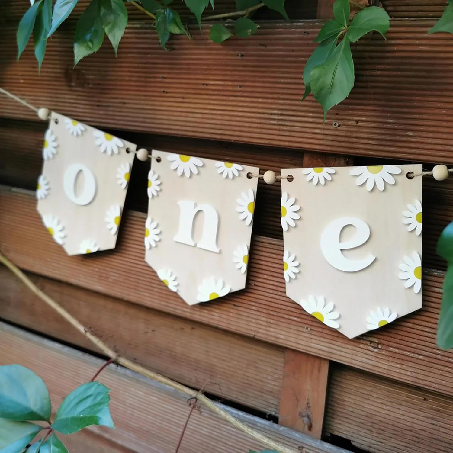 Decorative banner with 'one' and daisy patterns hanging on a wooden wall.