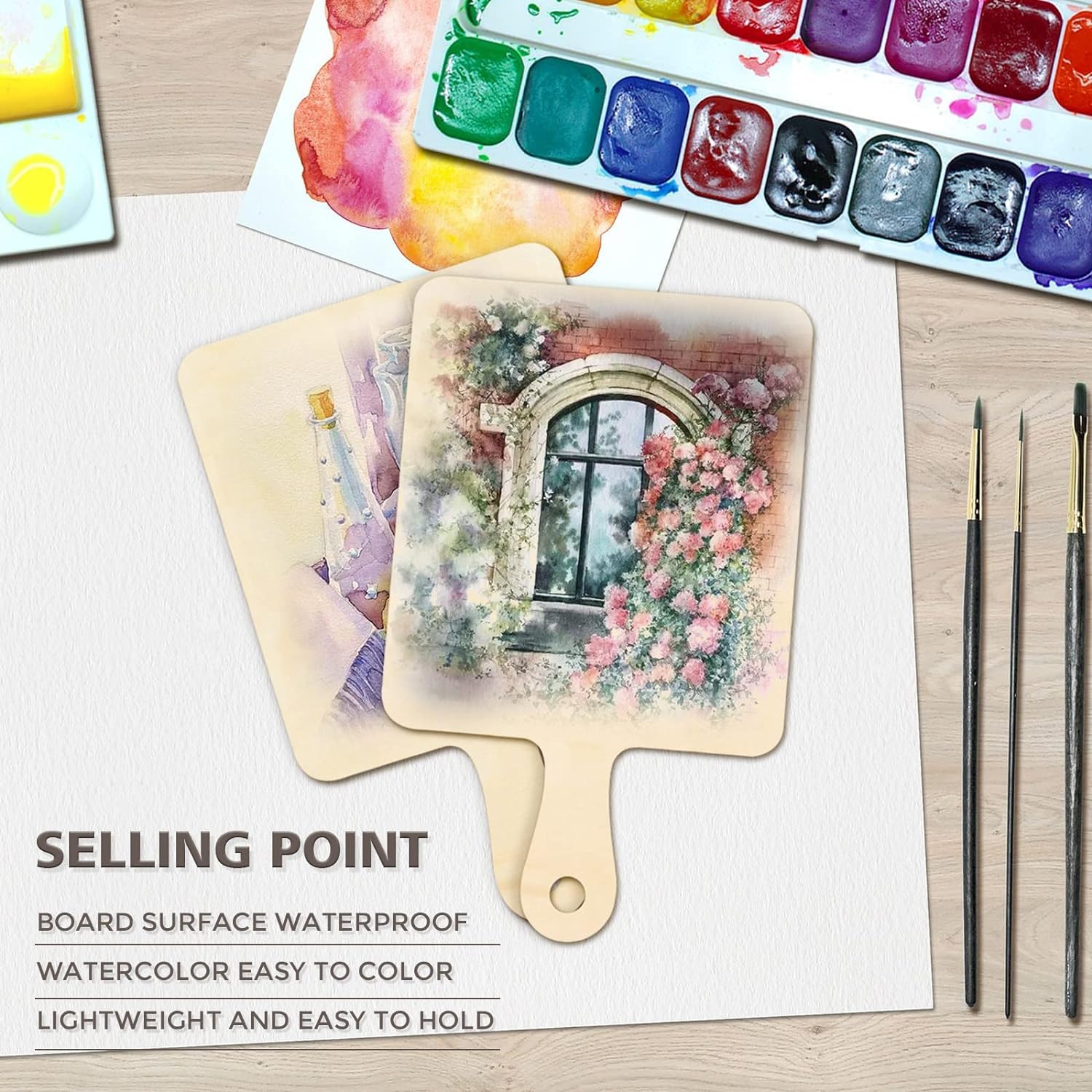 Painting of a floral arch on a wooden board with watercolor set and brushes on a table.