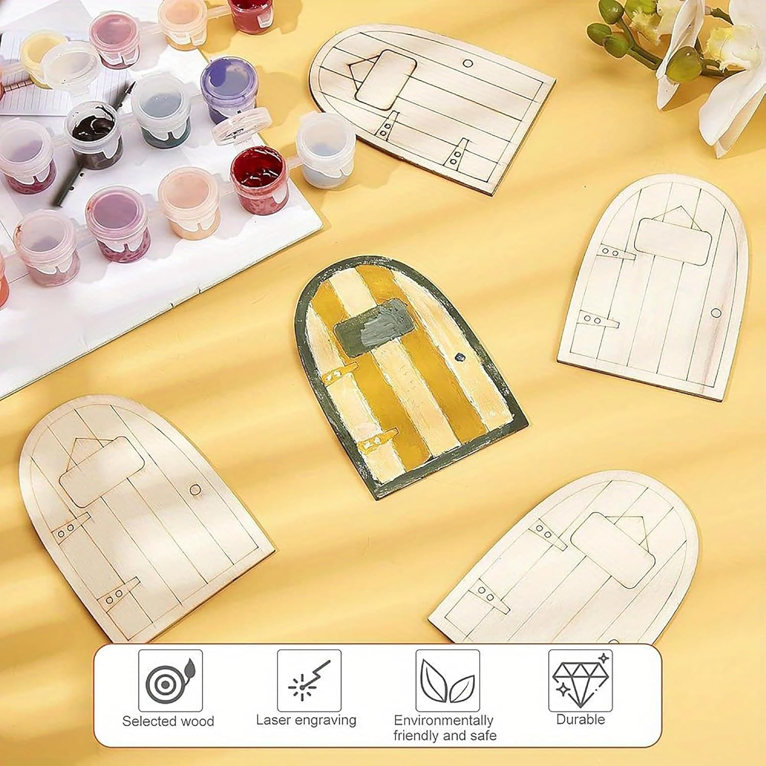 Wooden fairy doors with paint supplies on a yellow surface