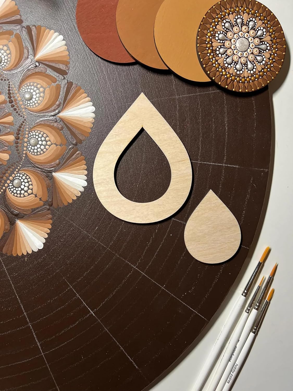 Wooden cutout shapes on a brown surface with color swatches and paintbrushes.