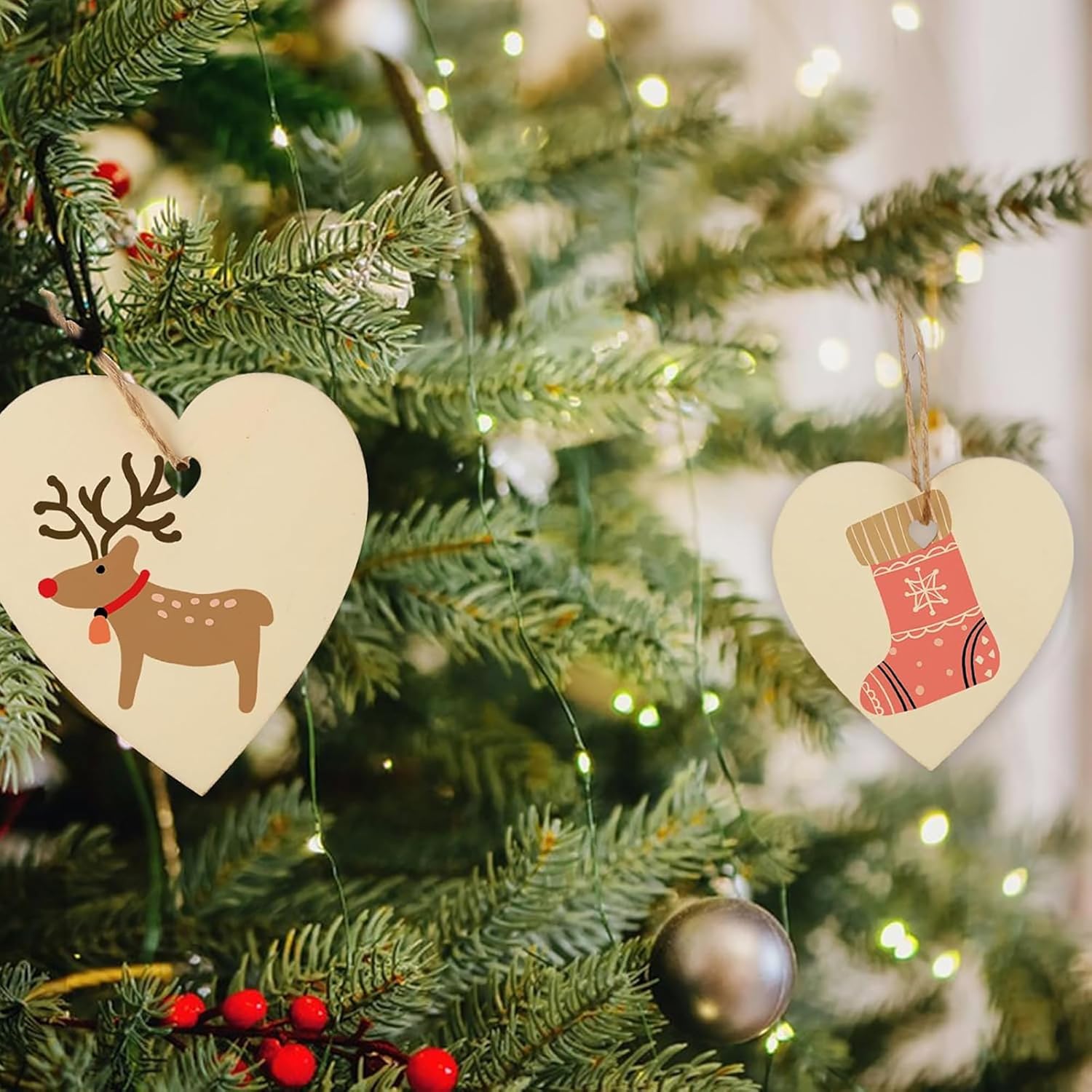 Heart-shaped Christmas ornaments with reindeer and stocking designs on a decorated tree.
