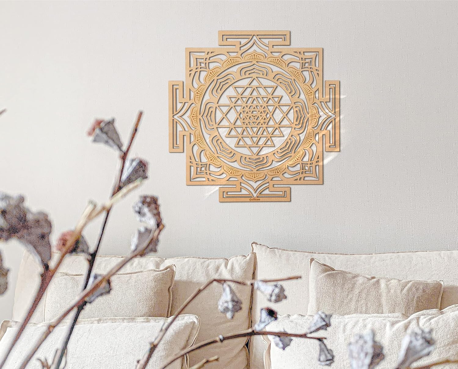 Decorative wall art with a geometric design on a light gray wall above a beige sofa.