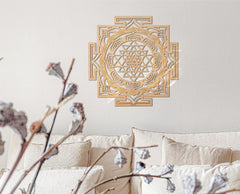 Decorative wall art with a geometric design on a light gray wall above a beige sofa.