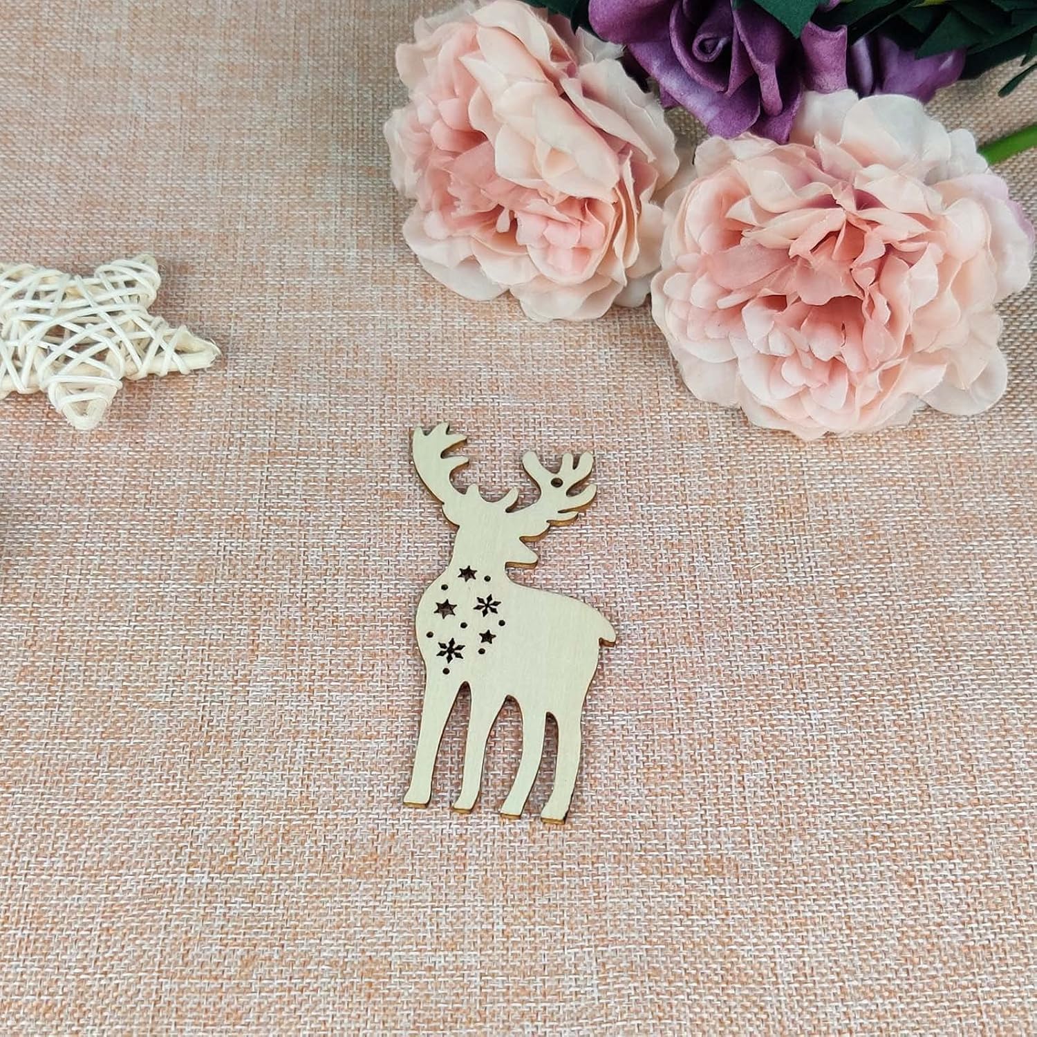 Wooden deer ornament on a textured surface with pink flowers