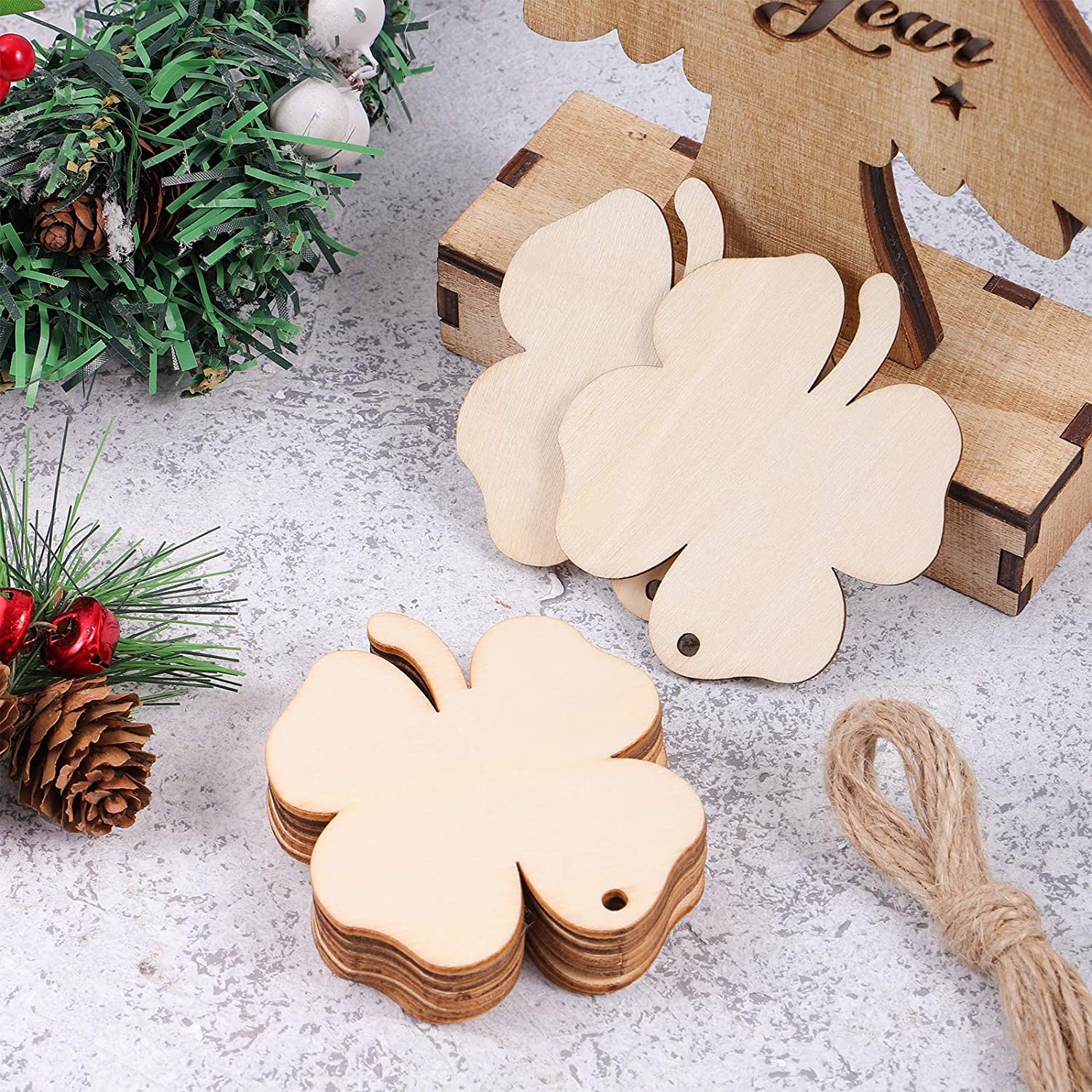 Wooden four-leaf clover tags on a textured surface with Christmas decorations.