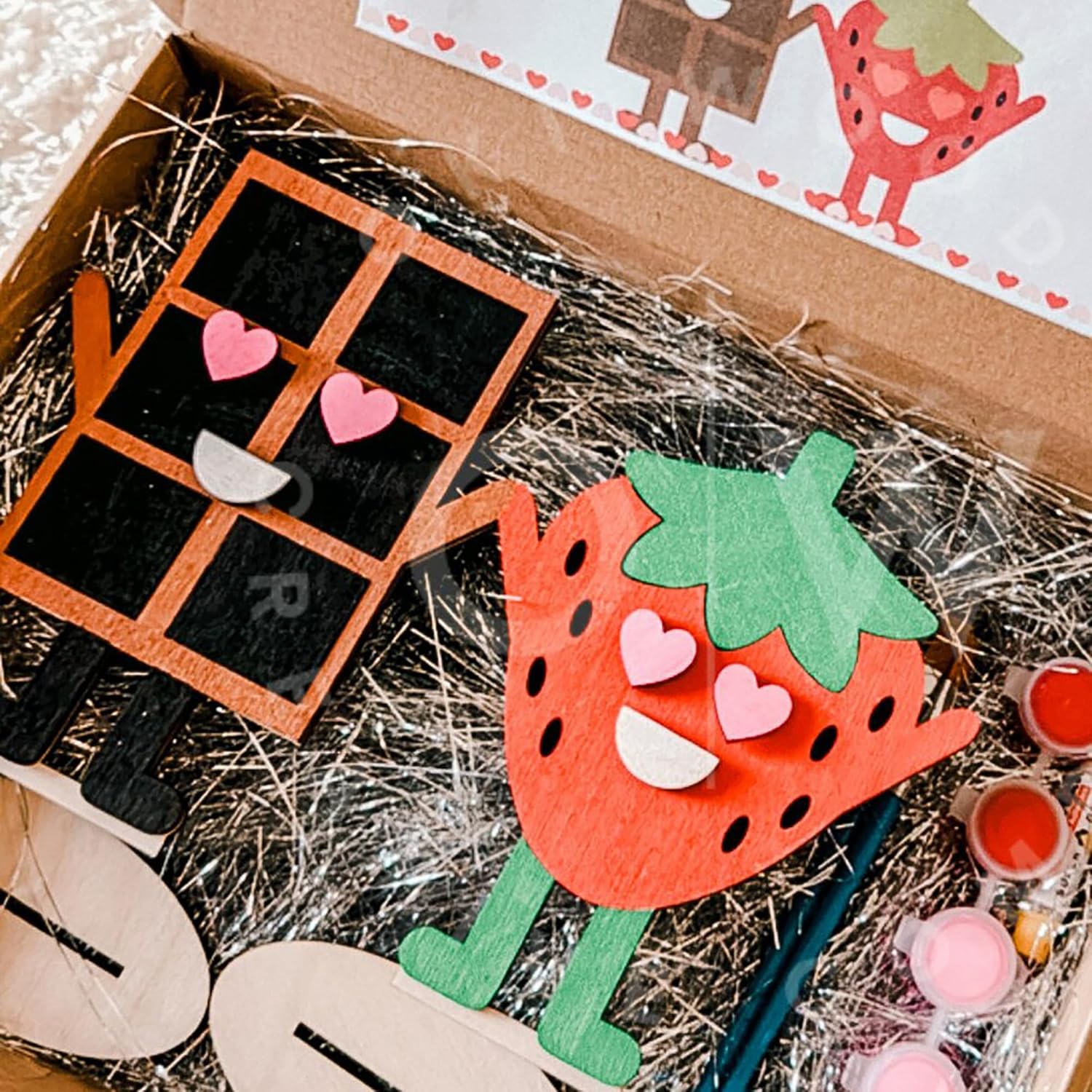 Craft kit with strawberry-shaped craft and materials on a textured surface
