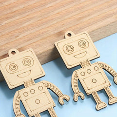 Two wooden robot-shaped pendants on a wooden and blue surface