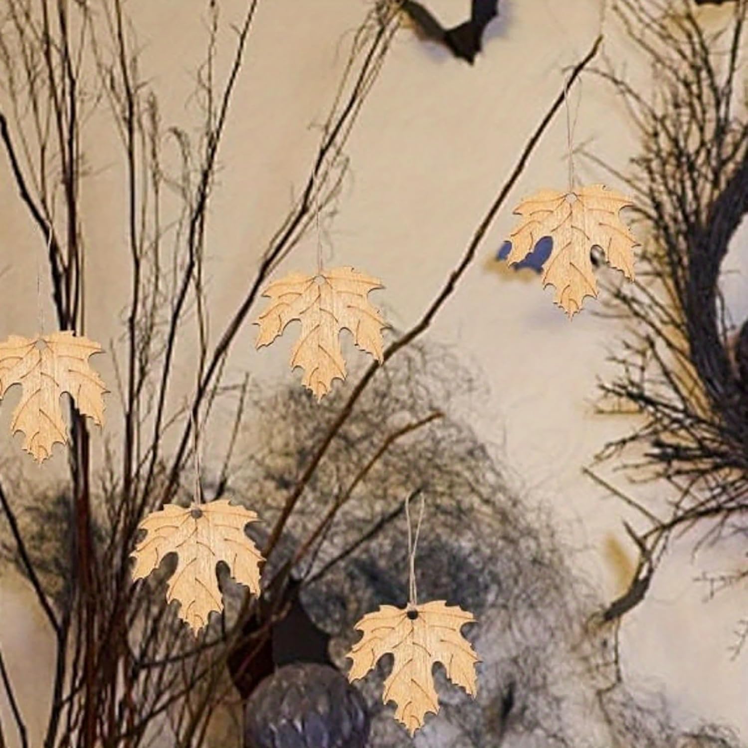 Decorative elements with leaf-shaped ornaments hanging from branches against a neutral background