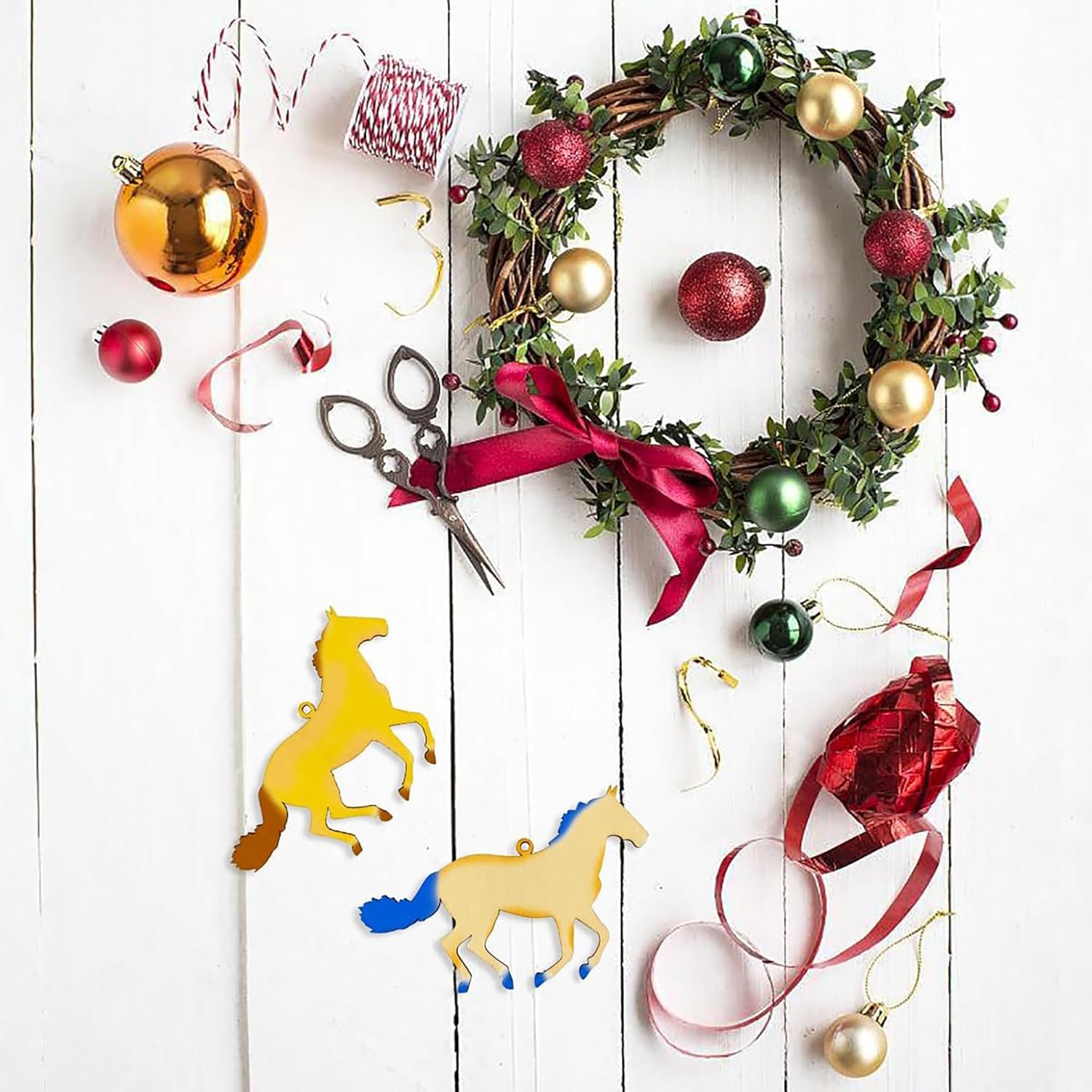 Decorative wreath with ornaments and scissors on a white wooden surface