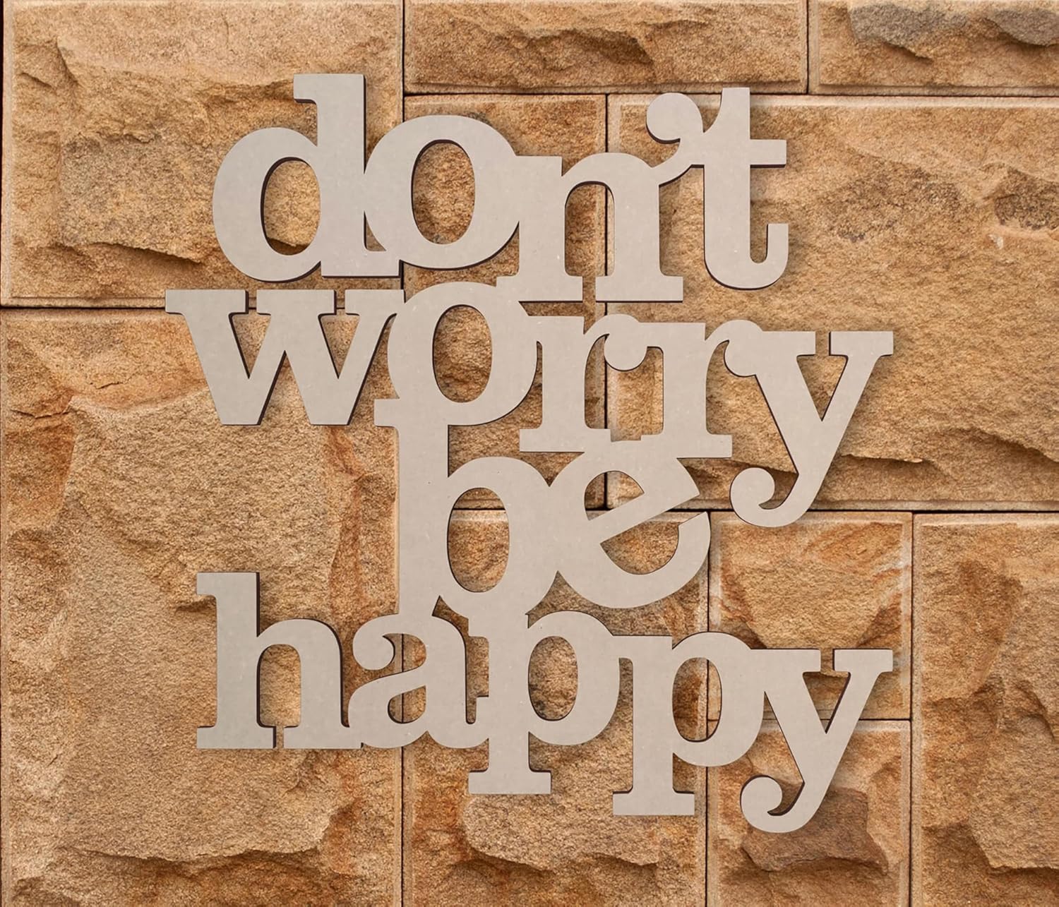 Decorative wall art with 'don't worry be happy' text on a stone background
