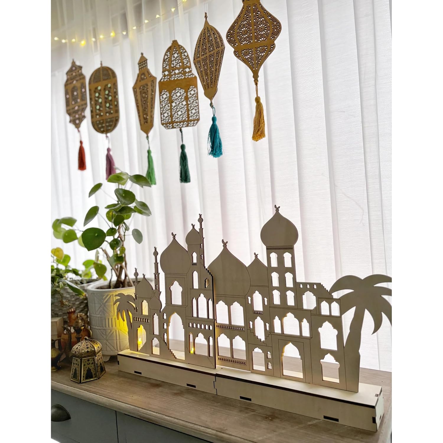 Decorative screen with architectural silhouette and hanging lanterns on a white curtain background