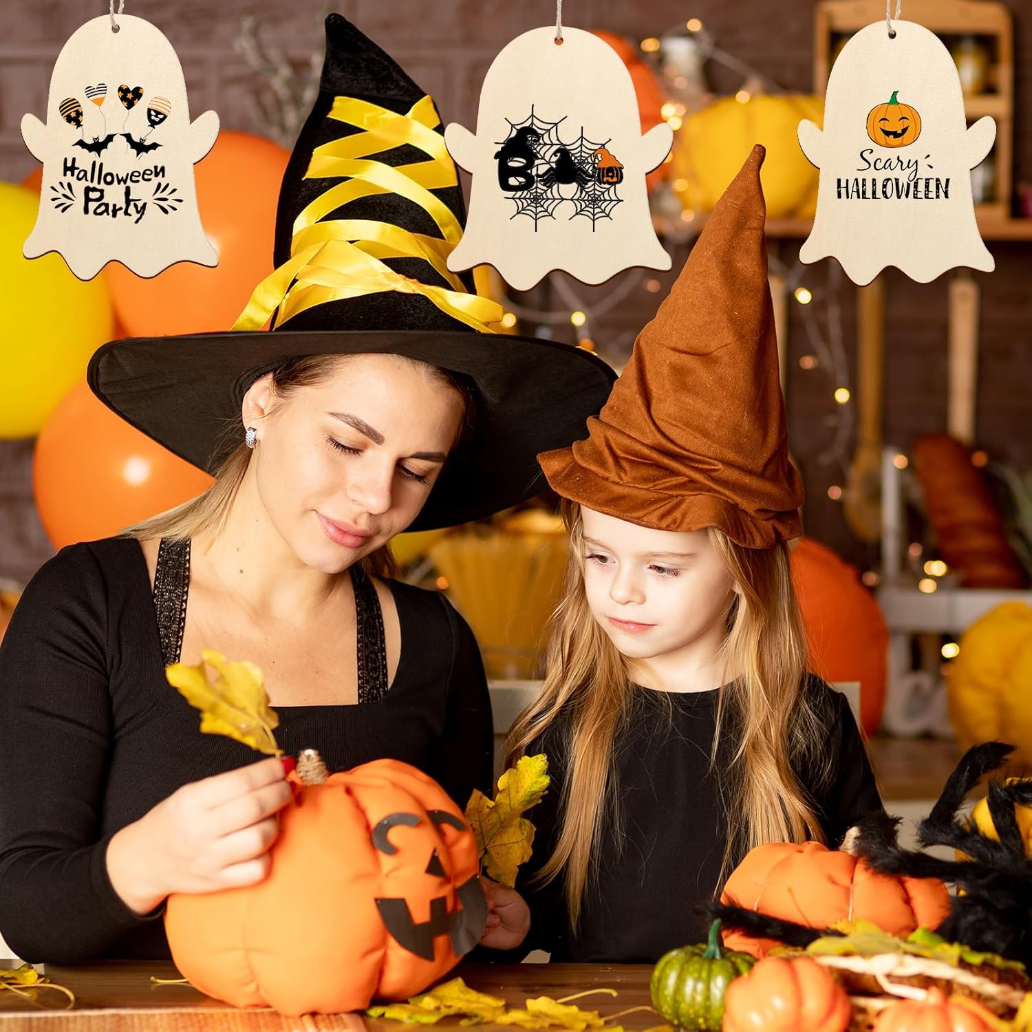 Woman and child in Halloween costumes with pumpkins and decorations.
