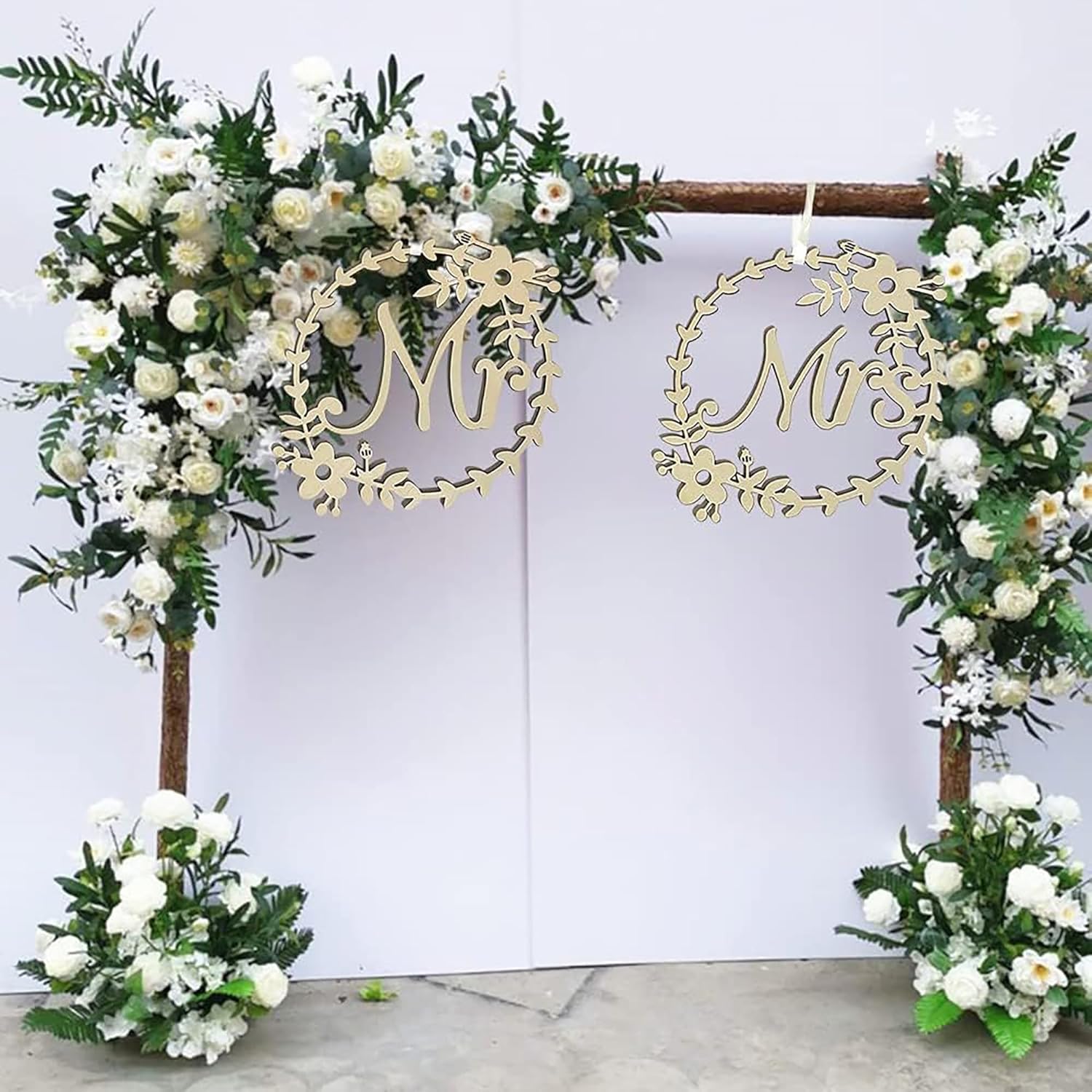 Decorative arch with floral arrangements and 'Mr' and 'Mrs' signs on a white background