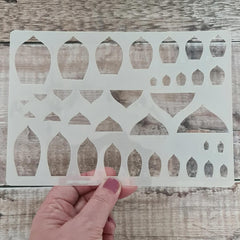 Decorative stencil held by a hand on a wooden surface