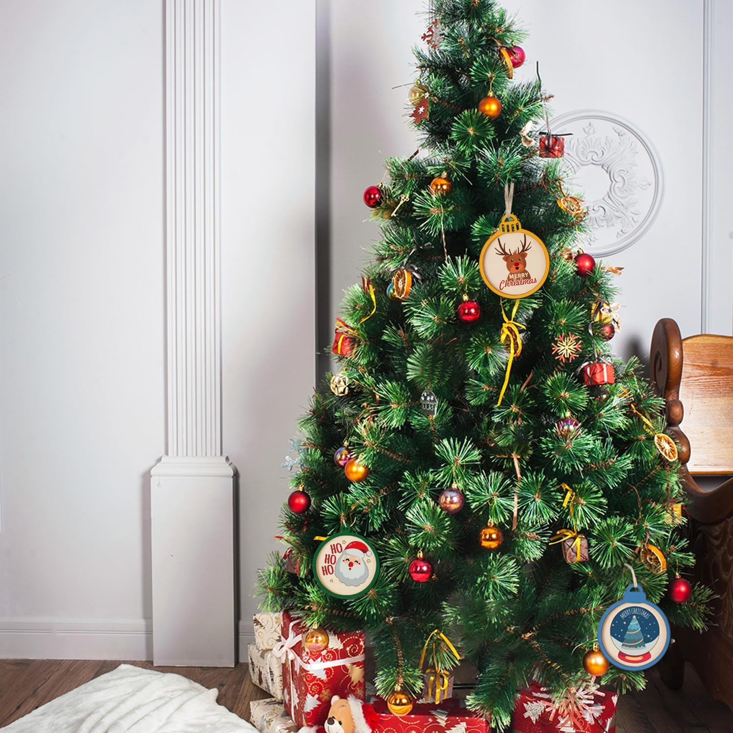 Decorated Christmas tree with ornaments and presents against a white wall.