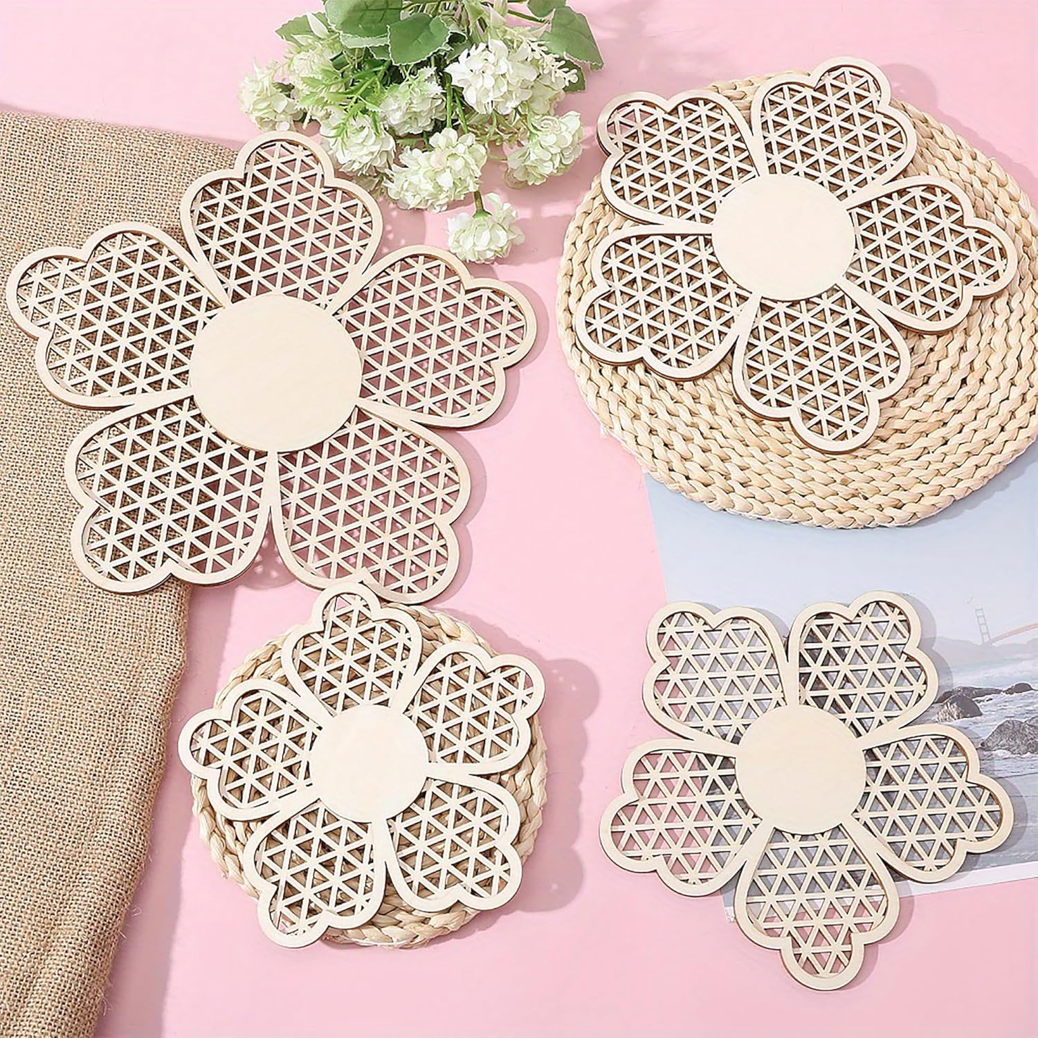 Floral-patterned woven coasters on a pink surface with flowers and fabric in the background