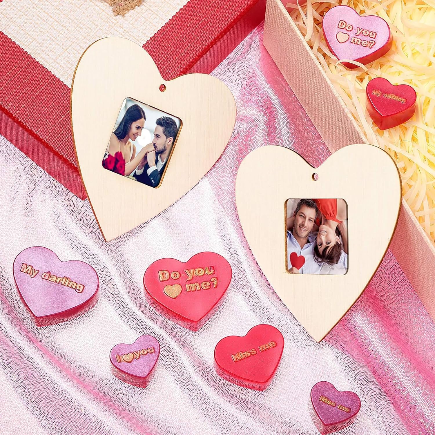 Heart-shaped photo frames and decorative pillows with romantic messages on a pink and white fabric background.