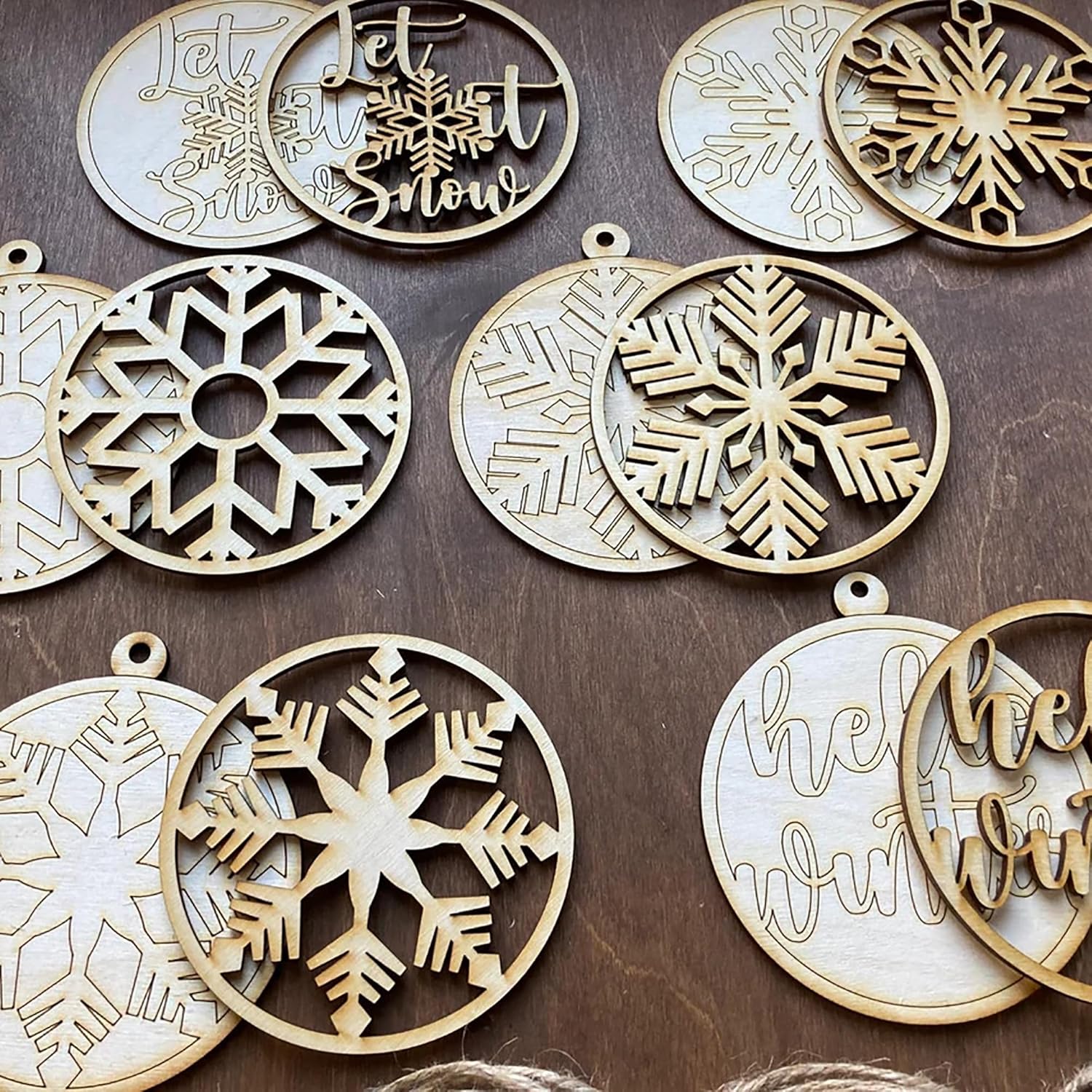 Wooden Christmas ornaments with snowflake designs and 'Let It Snow' text on a wooden surface.